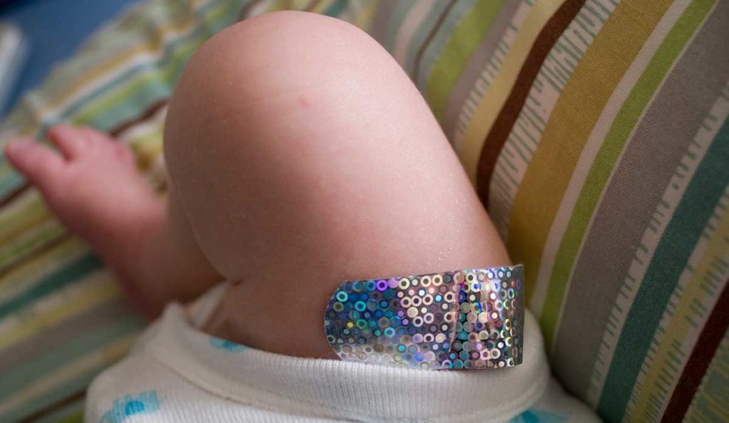Infants leg with a sparkly vaccination bandaid
