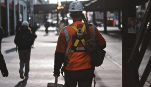 Construction worker in helmet carrying lunch cooler