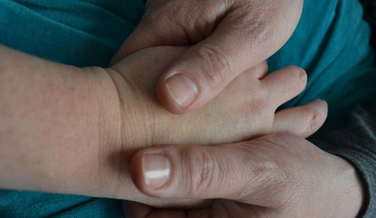 Doula's hands holding a patient's hands