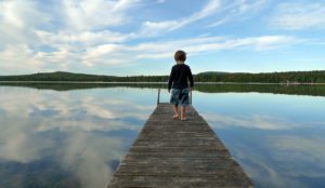 a child walking on a dock over water