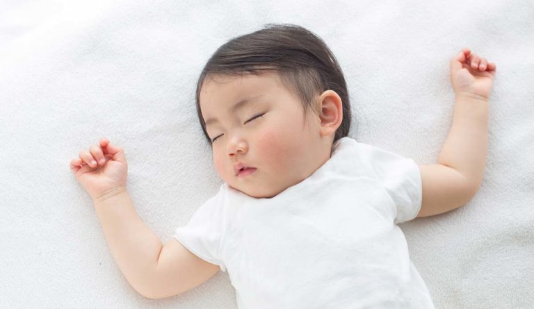 a baby sleeping on a white blanket