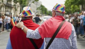 a man wearing a rainbow hat and a red shirt with his arm around another man