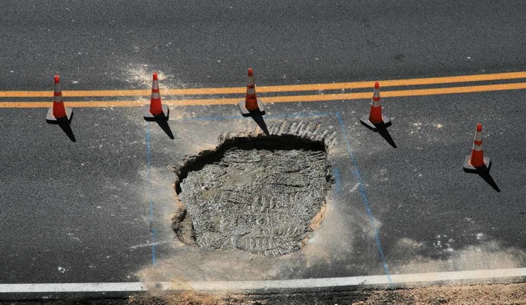 Sinkhole on a street with orange cones around it