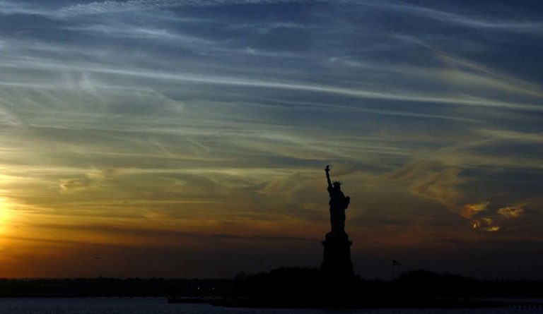 a statue of liberty with a sunset in the background