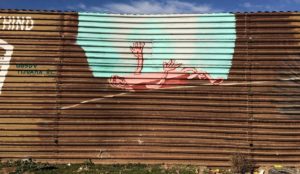 Mural painted on border wall of a gap with a person lying on their back, reaching toward blue sky