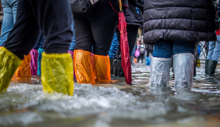 a group of people wearing rain boots and standing in water