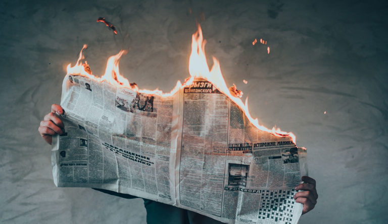 a person holding a newspaper on fire