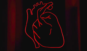 a red neon heart on a black background