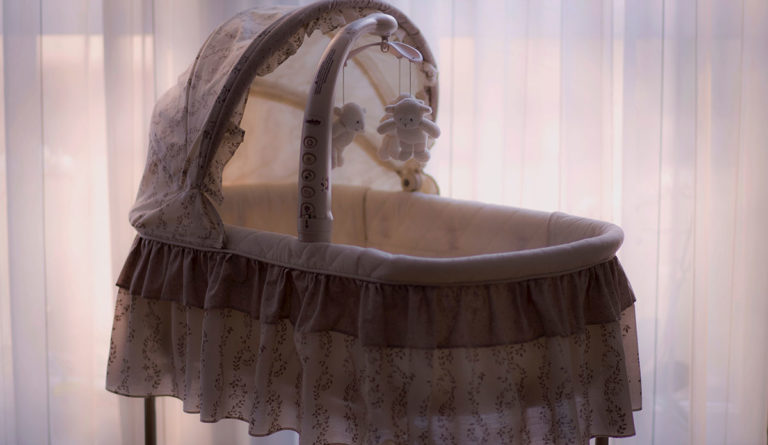 a baby cradle with a teddy bear from it