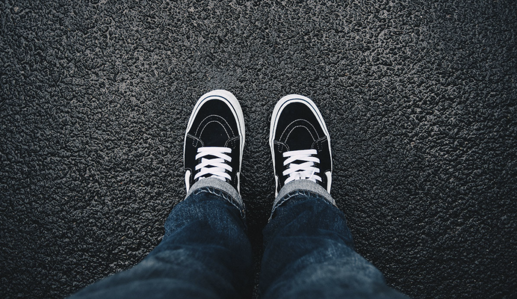 a person's legs and shoes on a wet road
