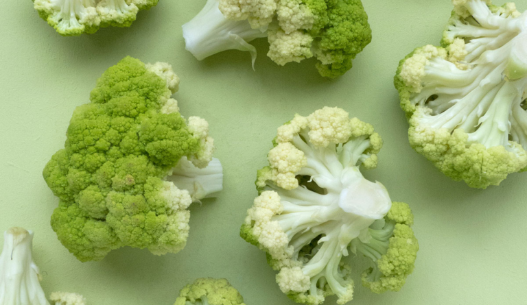 a group of broccoli on a green surface