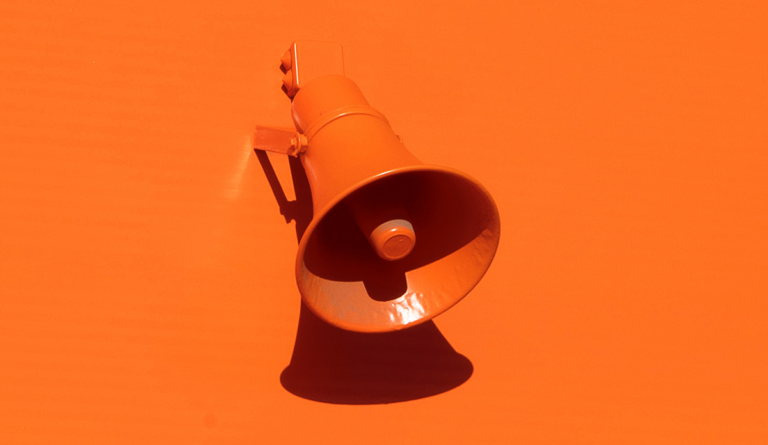 an orange speaker on a wall