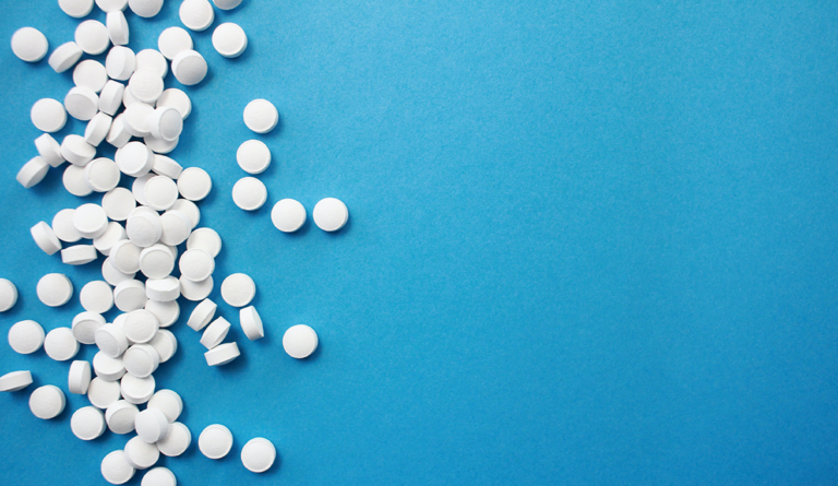 a group of white pills on a blue surface