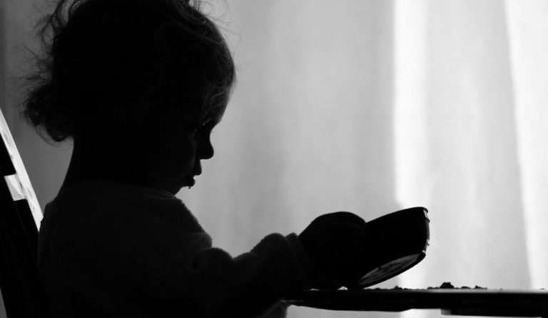 a silhouette of a child holding a cup