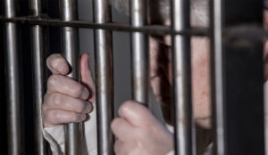 woman with gray hair behind prison bars