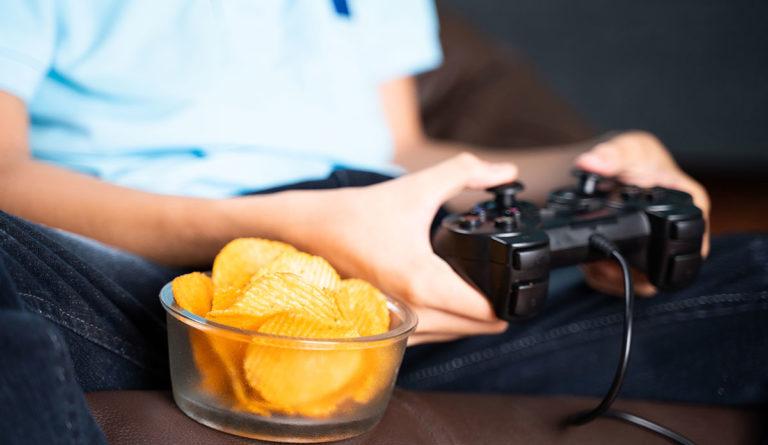 a person holding a game controller and potato chips