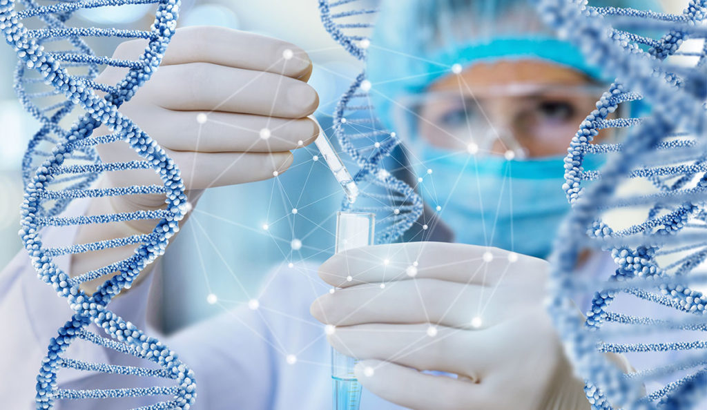 a person in a protective suit and gloves holding a test tube with a dropper