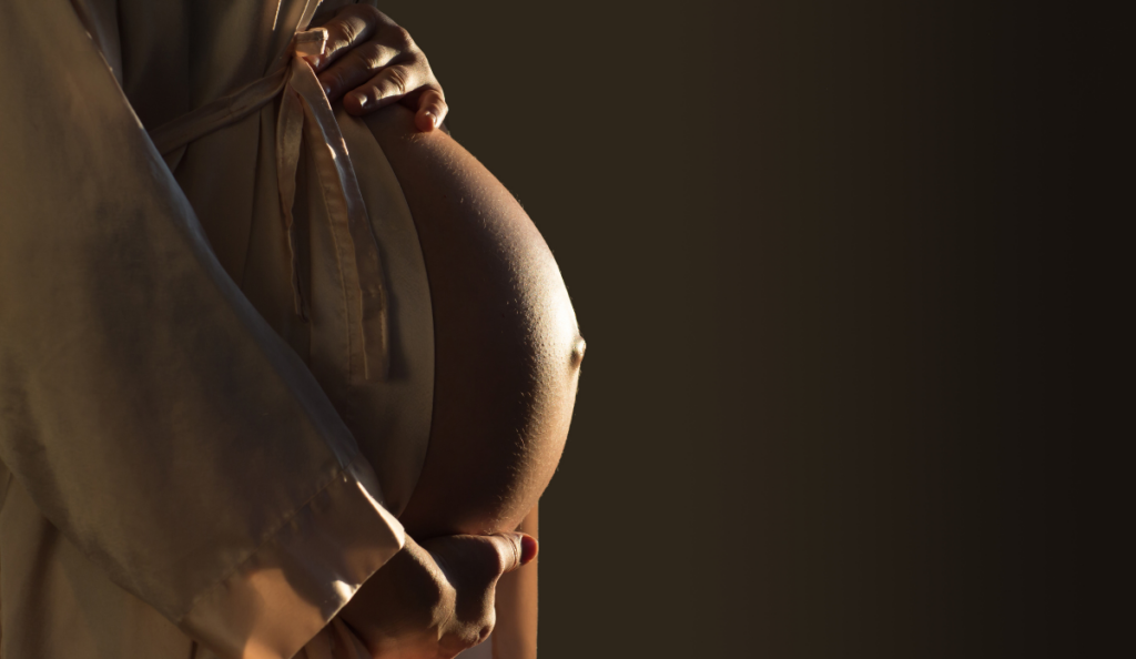 close up image of pregnant woman's growing baby bump