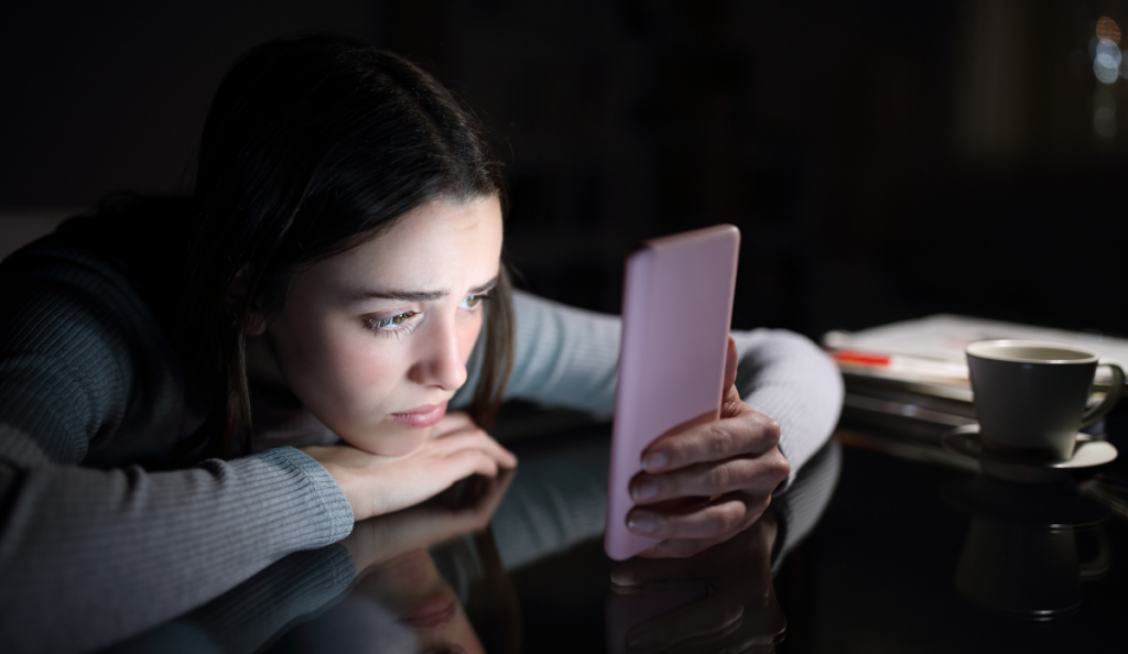 young, depressed girl scrolling through TikTok on her phone