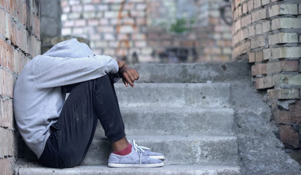 Young man sitting on stairs with head in hands, representing struggles with mental health