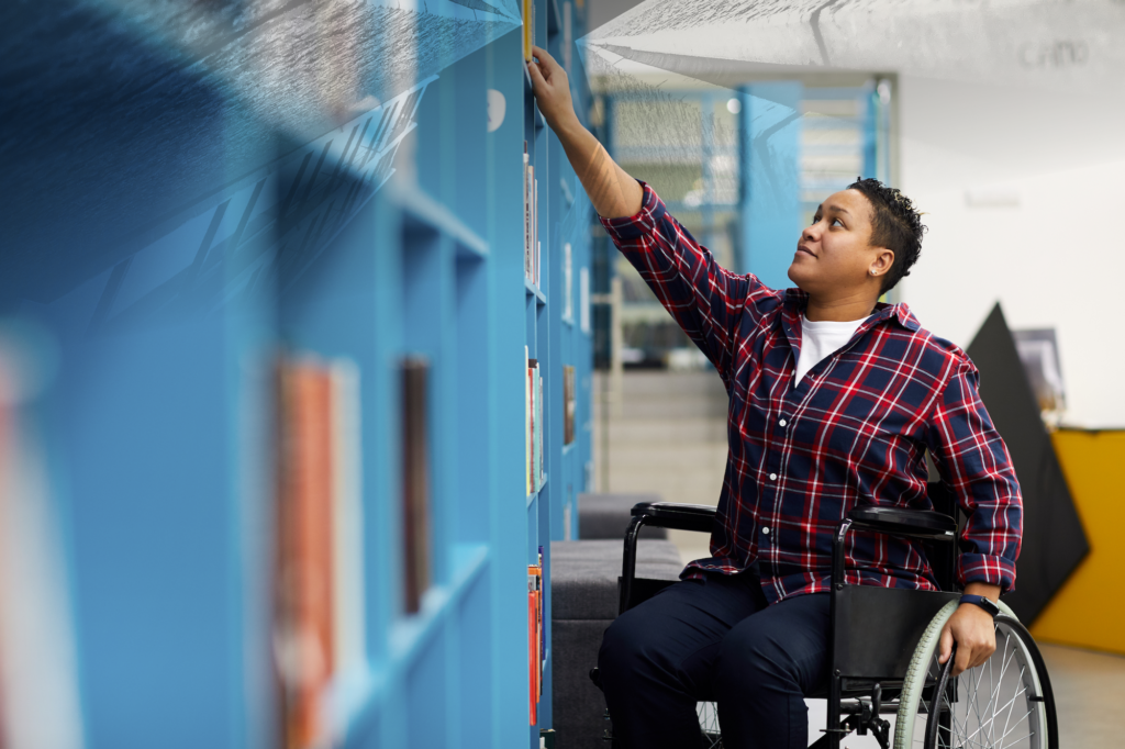a person in a wheelchair touching a book shelf