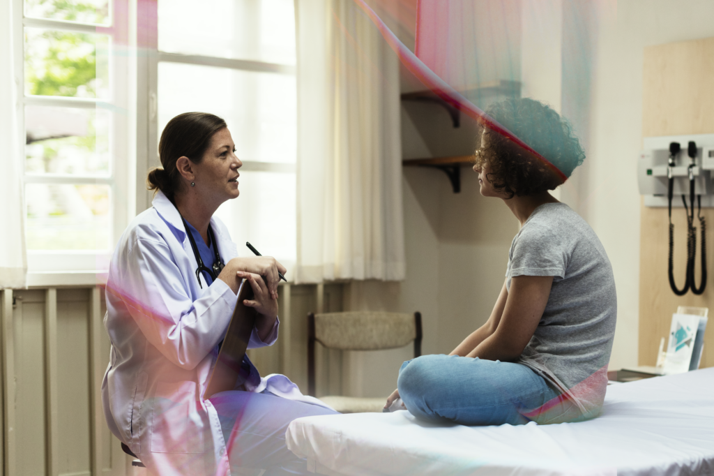 a woman sitting on a bed talking to a doctor
