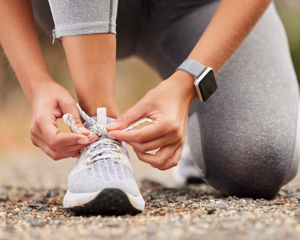 woman wearing an exercise tracker tying shoe before getting some movement in