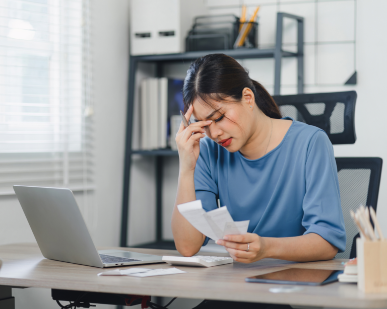 Stressed woman managing finances on laptop at home office