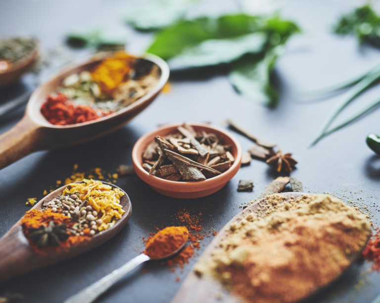 Shot of an assortment of spices in spoons and bowls on a table