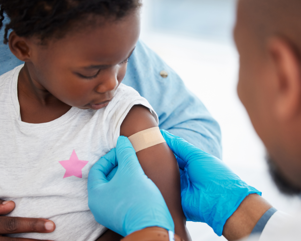 Young child receives vaccine from health care worker