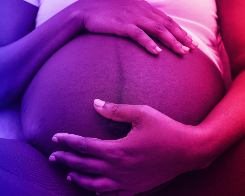 Photo of pregnant woman sitting with hands on stomach with a red and blue gradient filter. reproductive health concept