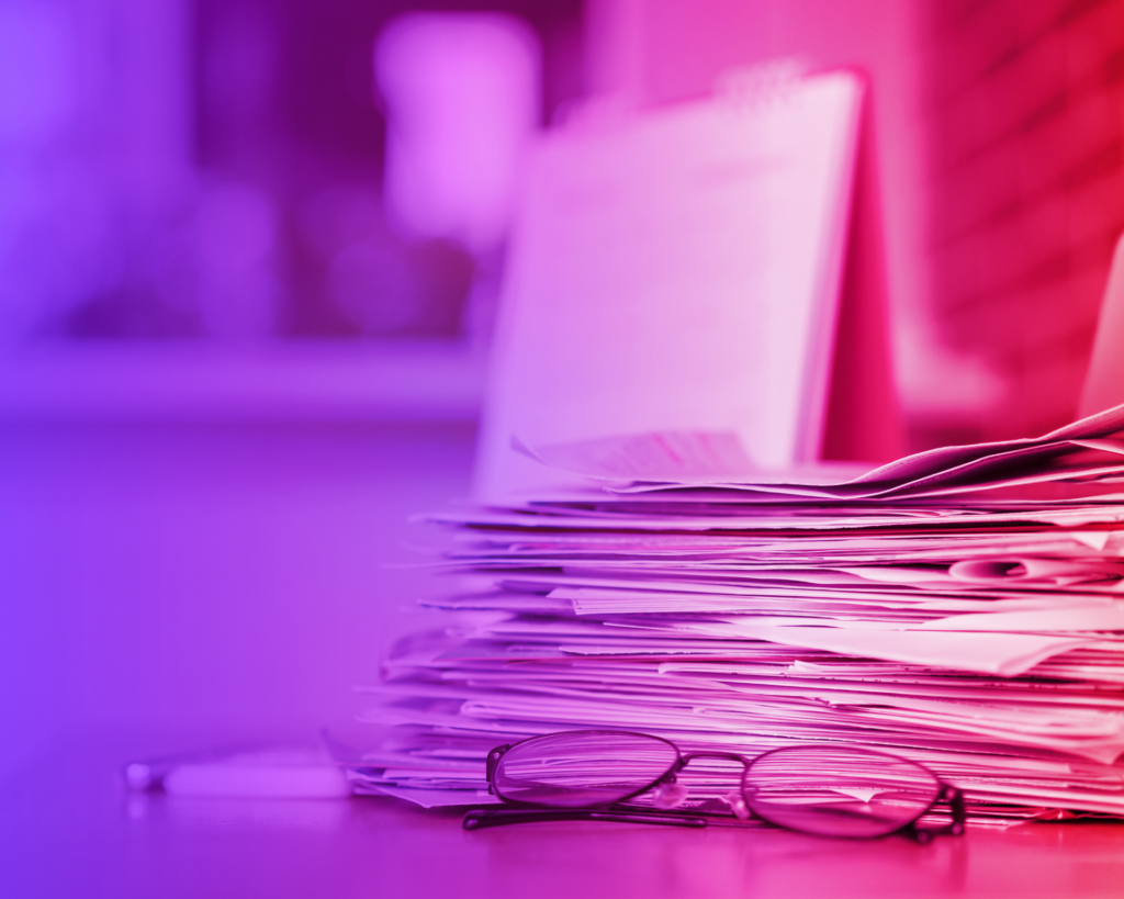 glasses in front of a stack of papers with a red and blue gradient filter. health coverage concept