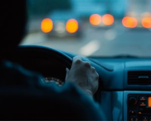 Hands on steering wheel; man driving a car by night