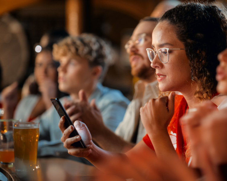 Young woman anxiously looking at phone in bar, betting on her favorite sports team. sports betting concept