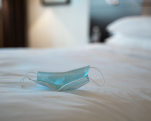 Close up shot of a protective facial disposable mask sitting on the bed in a hotel suite