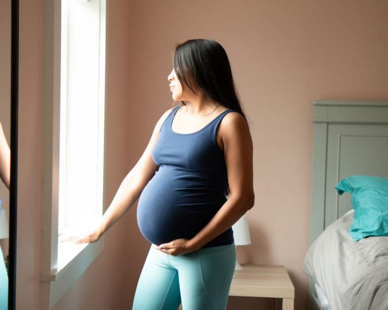 Young pregnant woman looking out the window