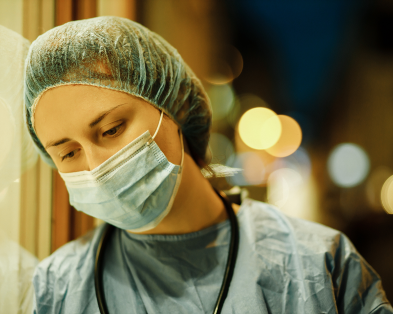 Tired nurse standing outside of hospital at night