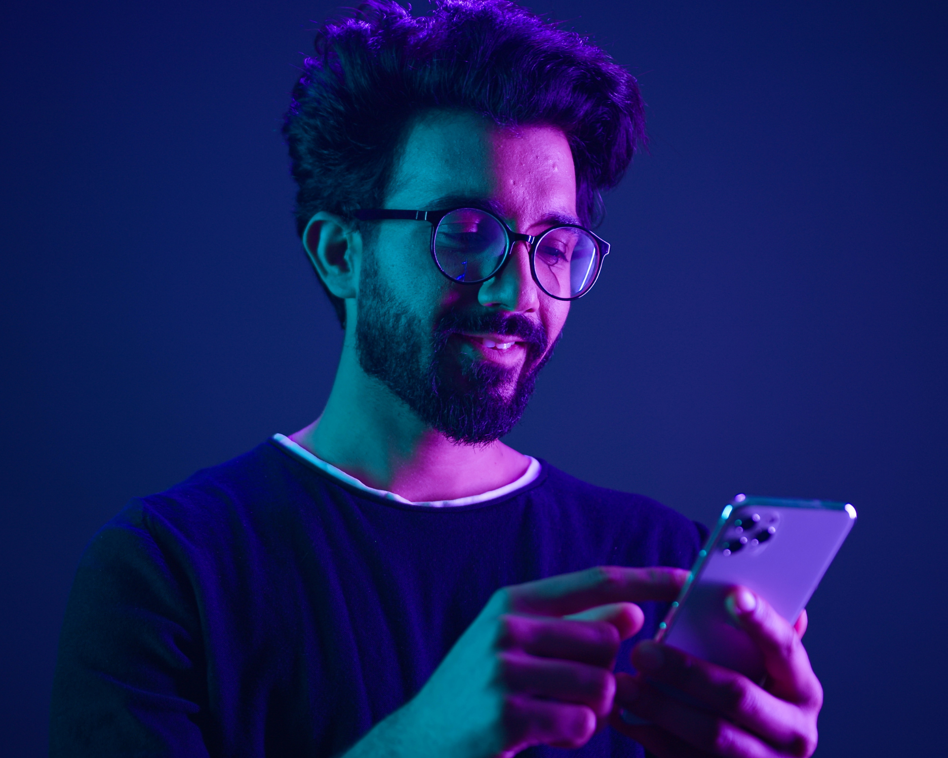 portrait of a young man scrolling through his phone with neon ultraviolet studio background