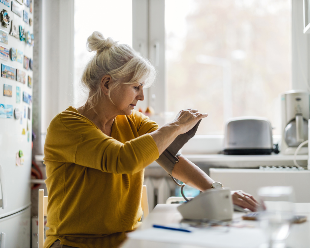Senior woman measuring blood pressure at home
