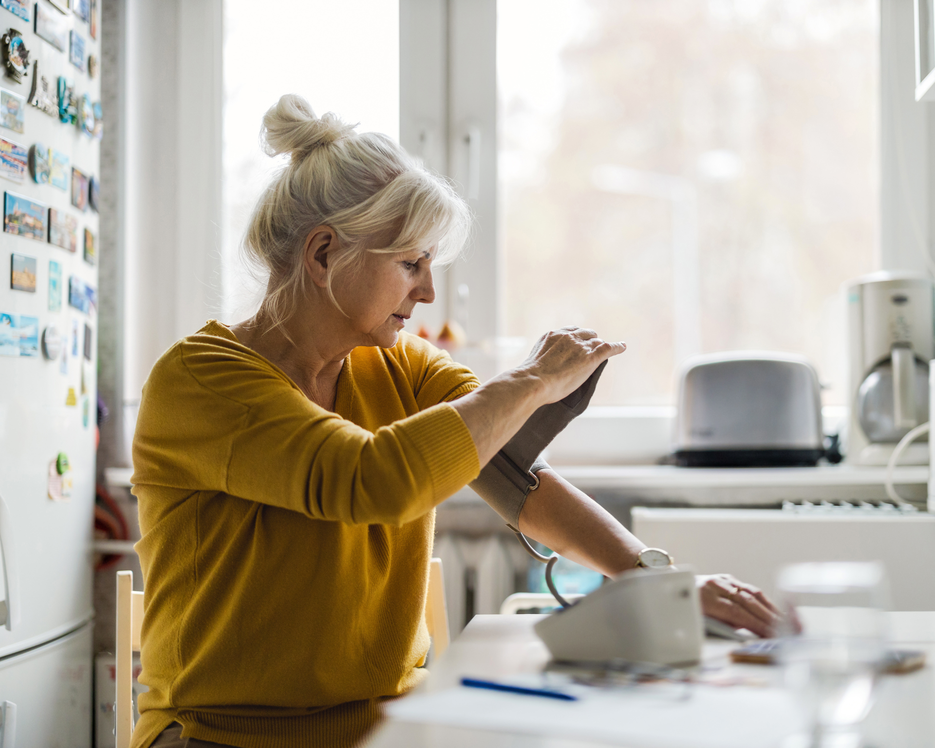 Senior woman measuring blood pressure at home