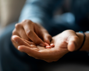 closeup image of Black man holding medication in hands; antidepressant concept
