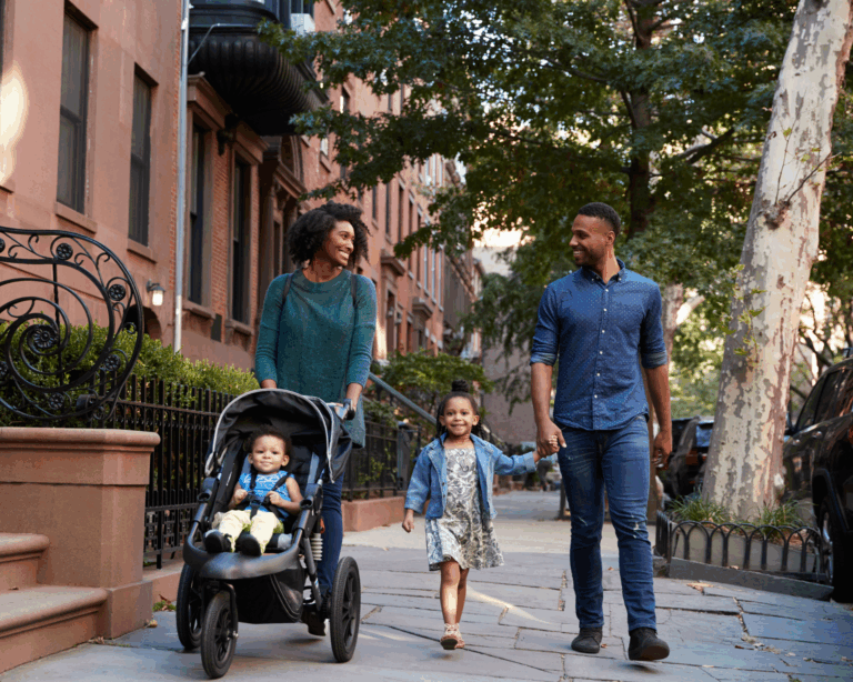 portrait of a young family walking on tree-lined street