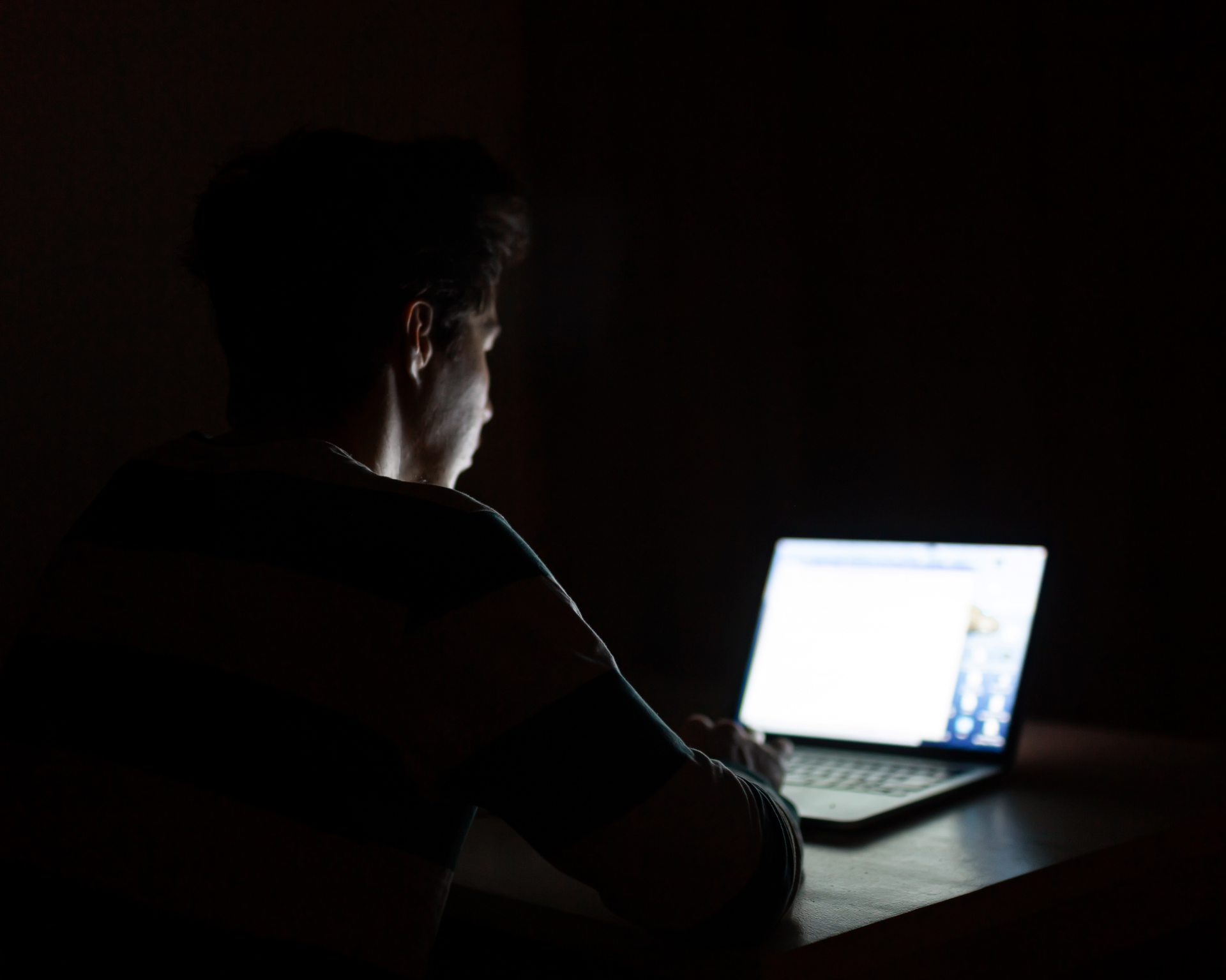 young man on computer in dark room. manosphere concept