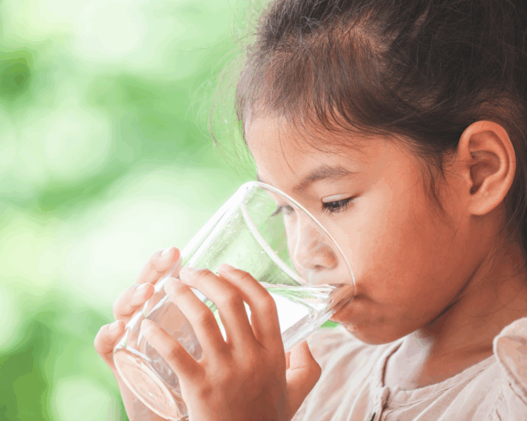 Close-up of young girl drinking water from a glass outdoors