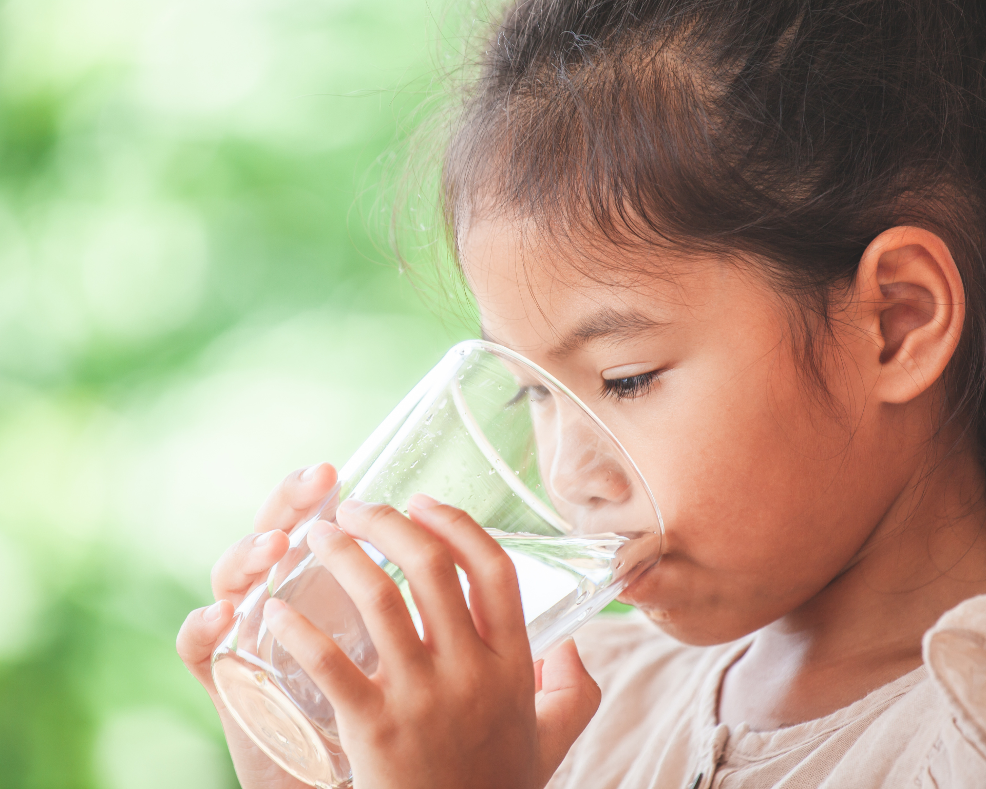 Close-up of young girl drinking water from a glass outdoors