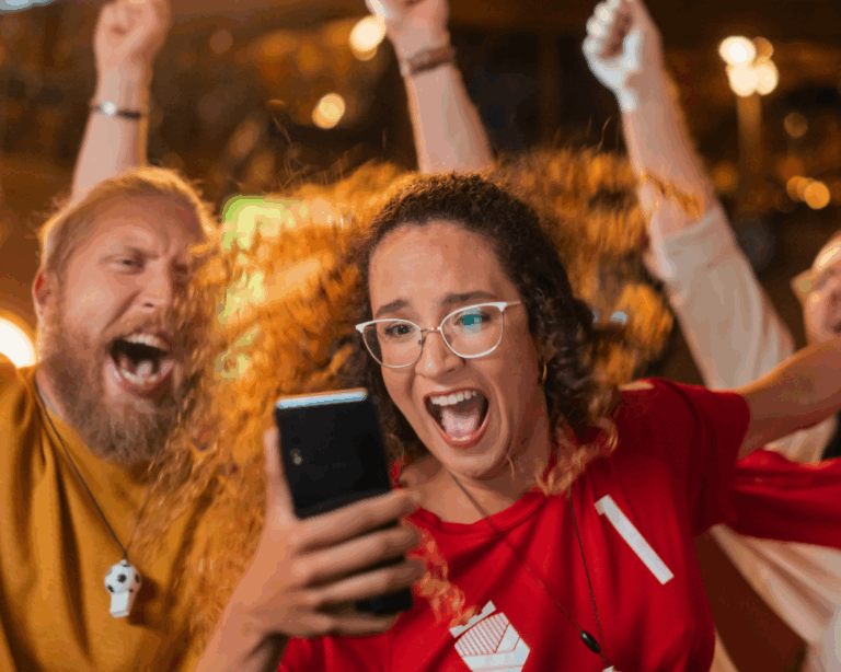 Portrait of a young woman holding smartphone at bar, cheering after betting on her favorite sports team. Sport gambling concept