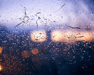 Bullet holes in glass against the background of a blurred city close up. Mass shooting concept