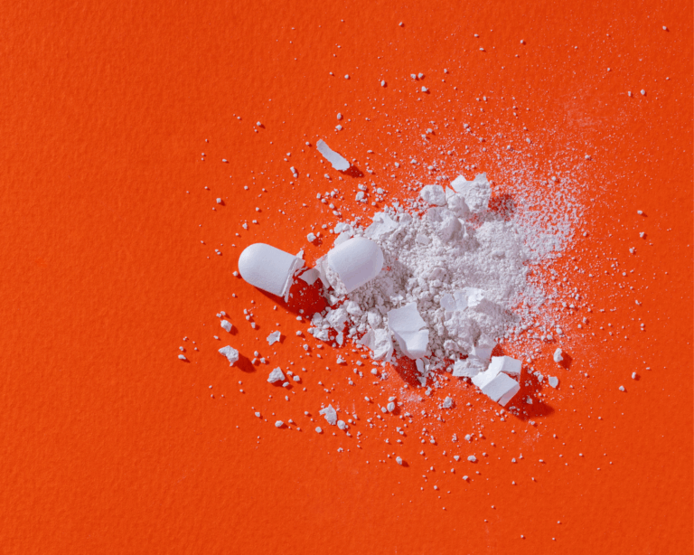 shattered white pills on a bright orange background