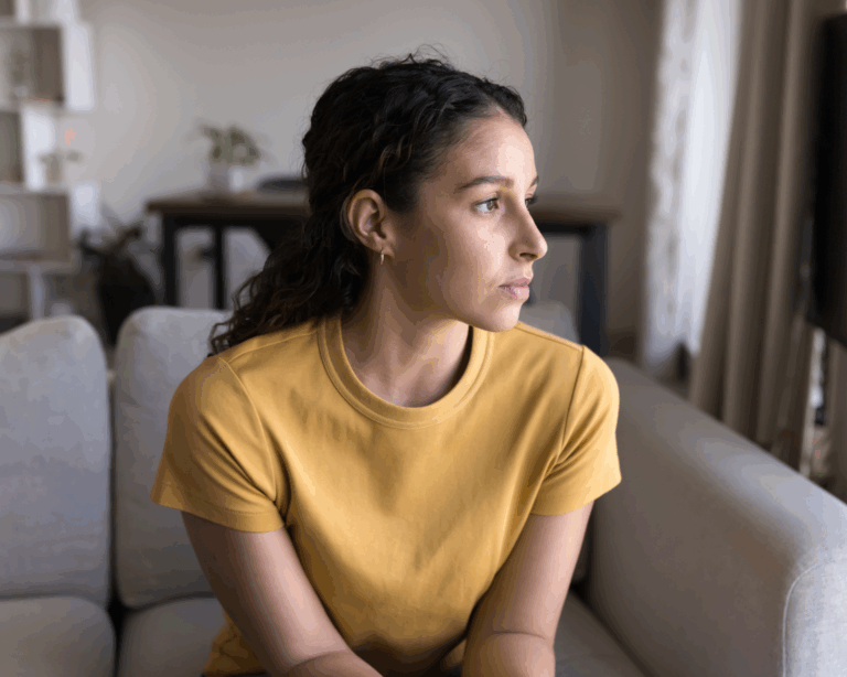 Portrait of a young woman sitting on a couch and looking out the window. Mental health and women's health concept
