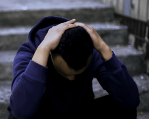 young man sitting on the stairs with his head in his hands